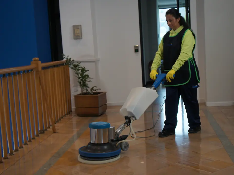 Trabajador de CleanVip abrillantando un piso de madera en un pasillo
